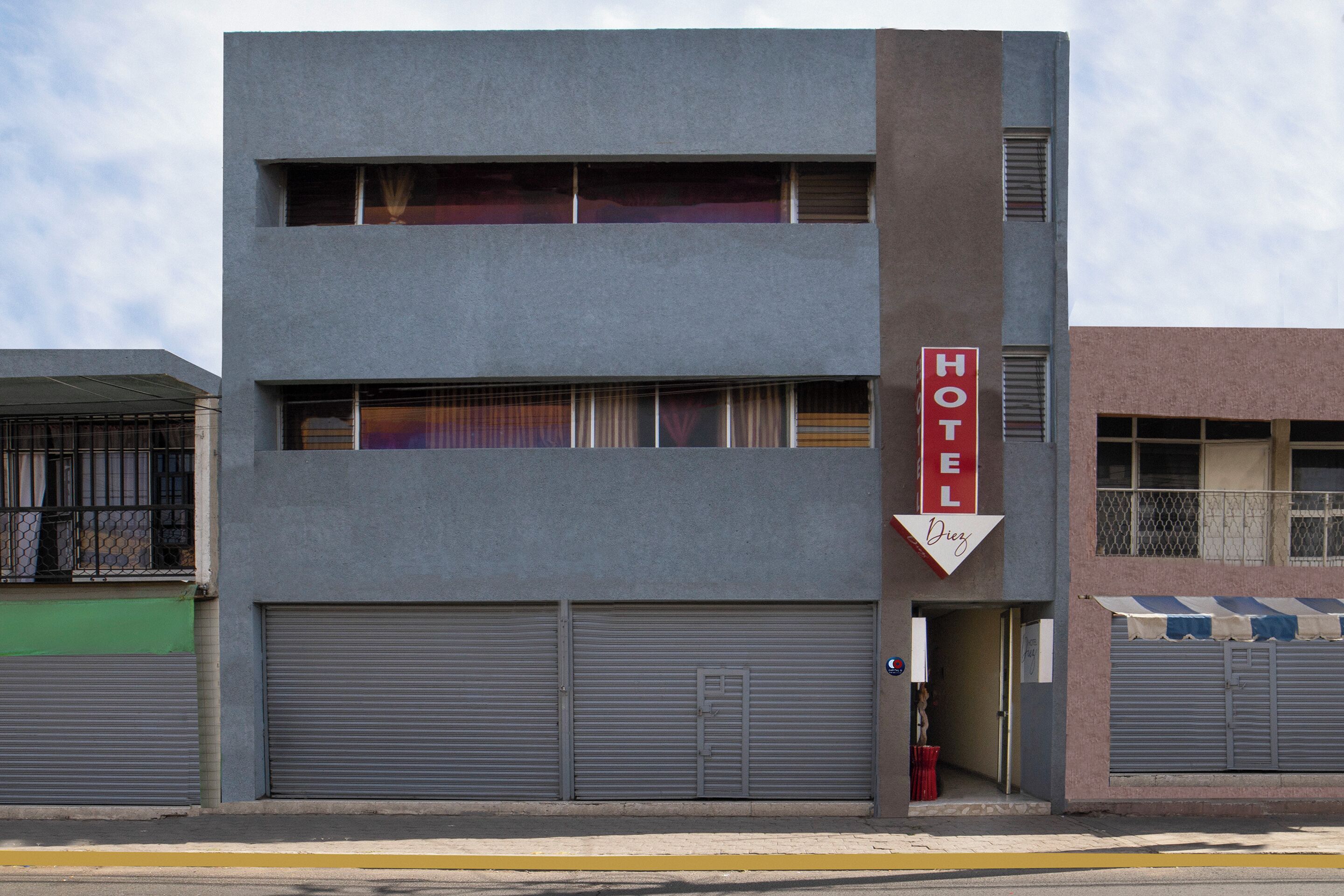A hotel with a modern design, featuring two ground-level garages and a prominent 'HOTEL' sign.