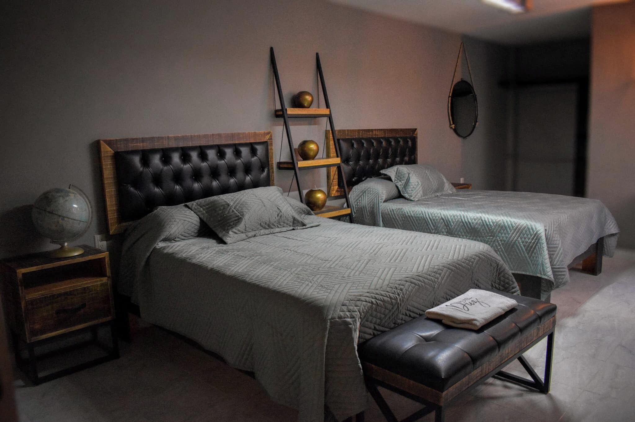 A bedroom with two beds, a globe on a nightstand, and a ladder shelf with decorative items.