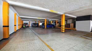 Ett underjordiskt parkeringsgarage med flera våningsplan, utmärkt av gula och svarta pelare, och ett klinkergolv.