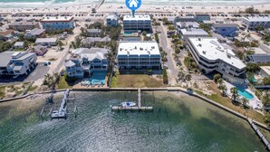 An aerial view of a coastal hotel with multiple buildings, a dock, and a beach in the background. - Beach View - Pelican Cove 3 by SeaBreeze Vacation (Bradenton Beach)