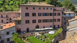 A pink building with a courtyard, outdoor seating, and a view of surrounding buildings and hills.