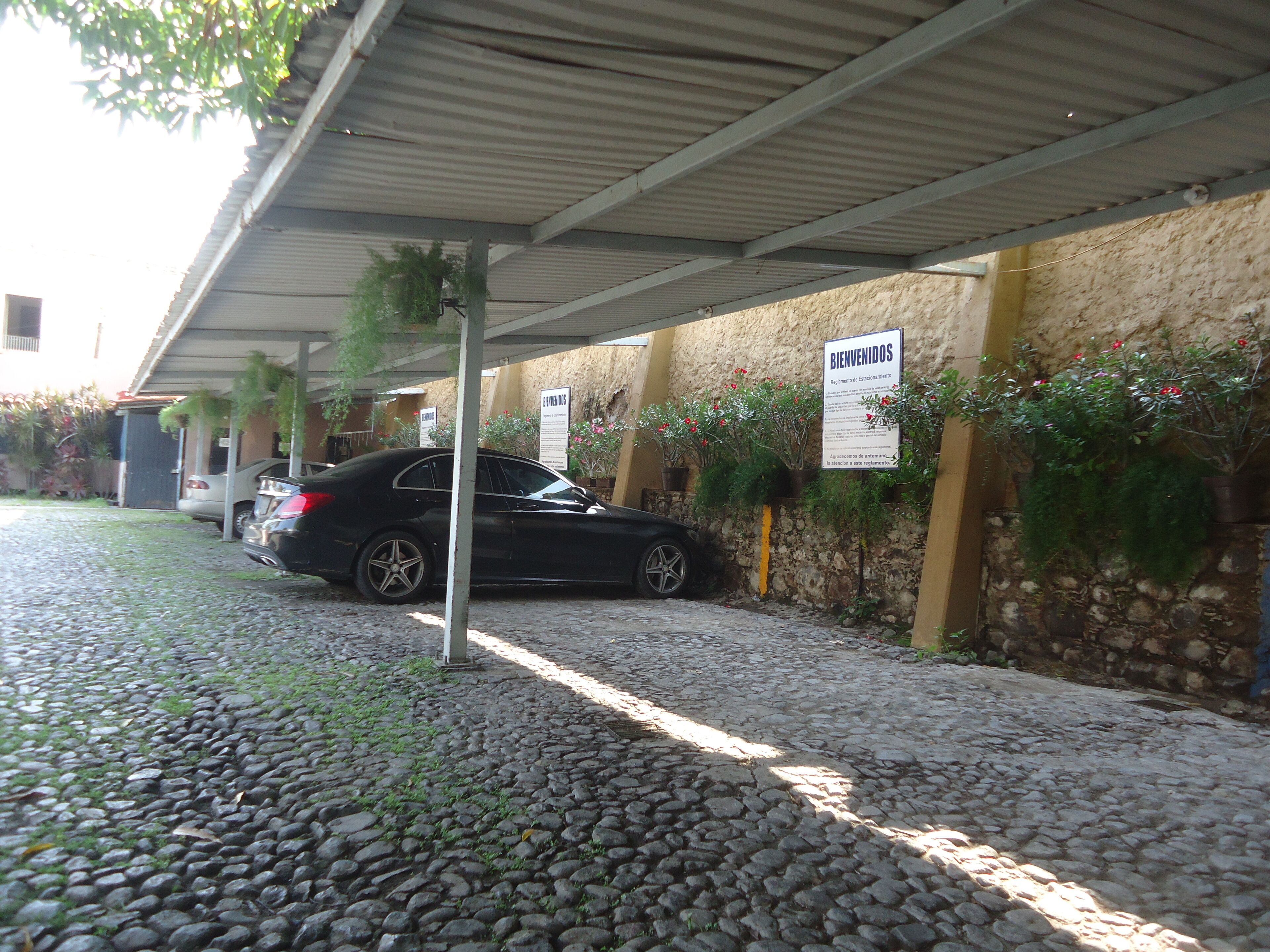 Ein überdachter Parkbereich mit Steinmauer und Schild zur Begrüßung der Besucher.