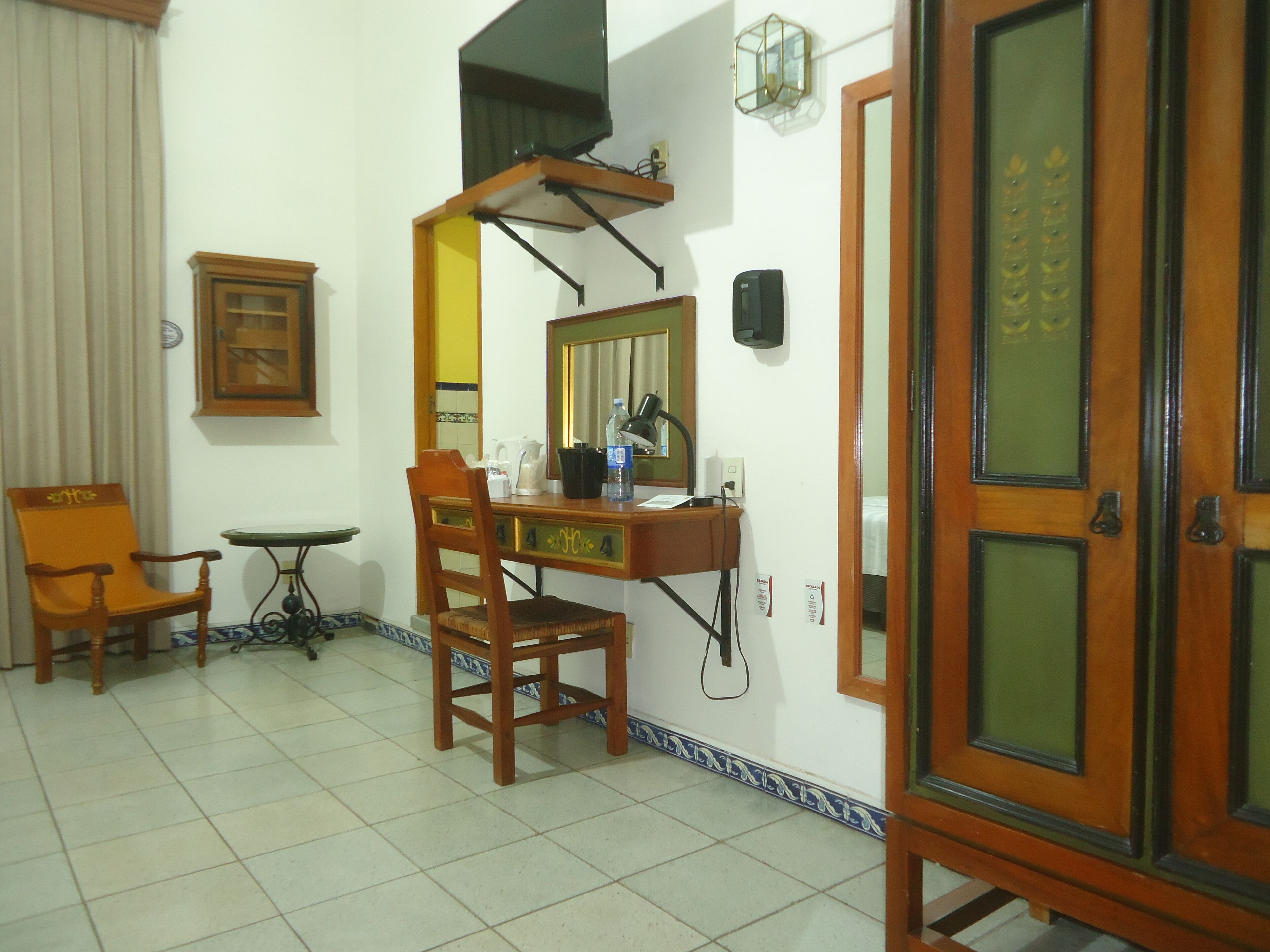 A room with a desk, chair, and a large mirror.