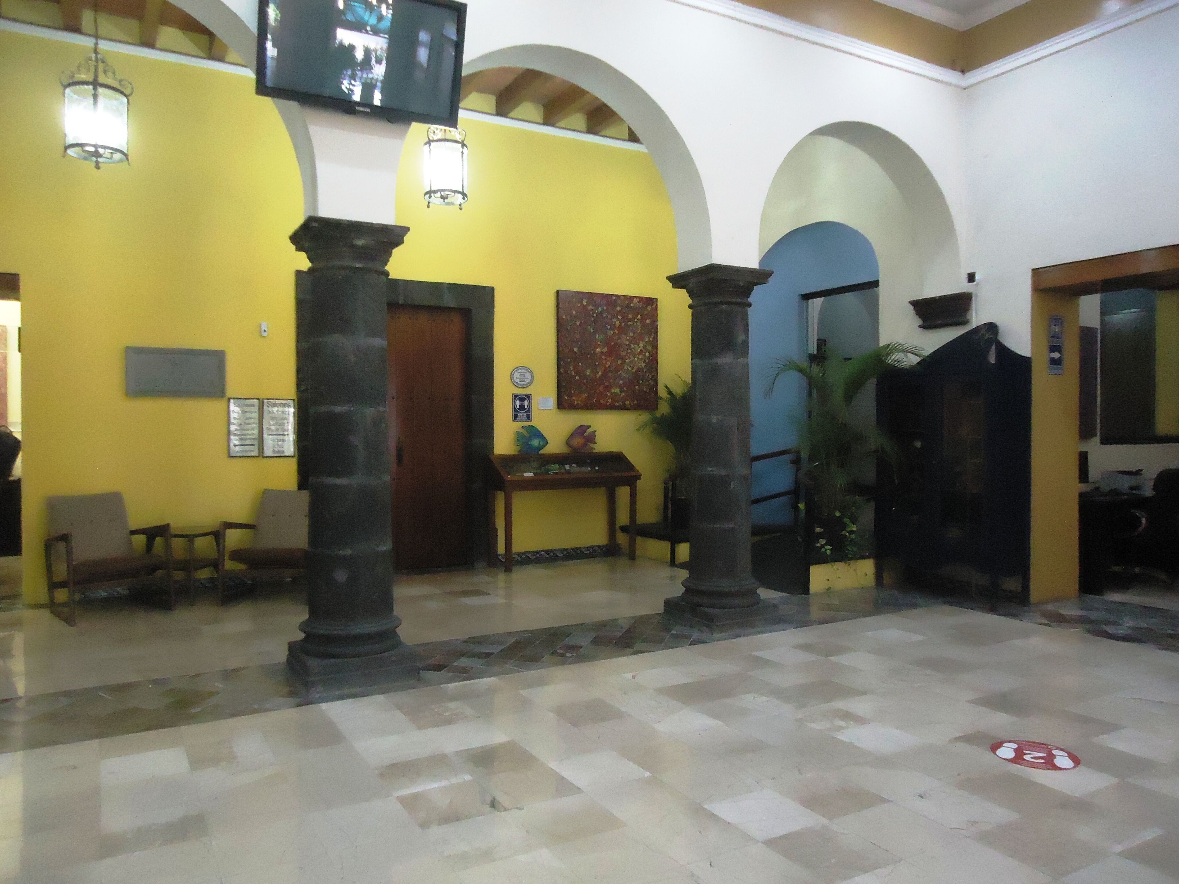 A lobby with yellow walls, a checkered floor, and a wooden reception desk.