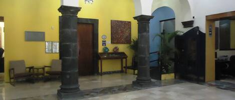 A lobby with yellow walls, a checkered floor, and a wooden reception desk.