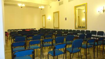 A conference room with rows of blue chairs, a large mirror, and chandeliers.