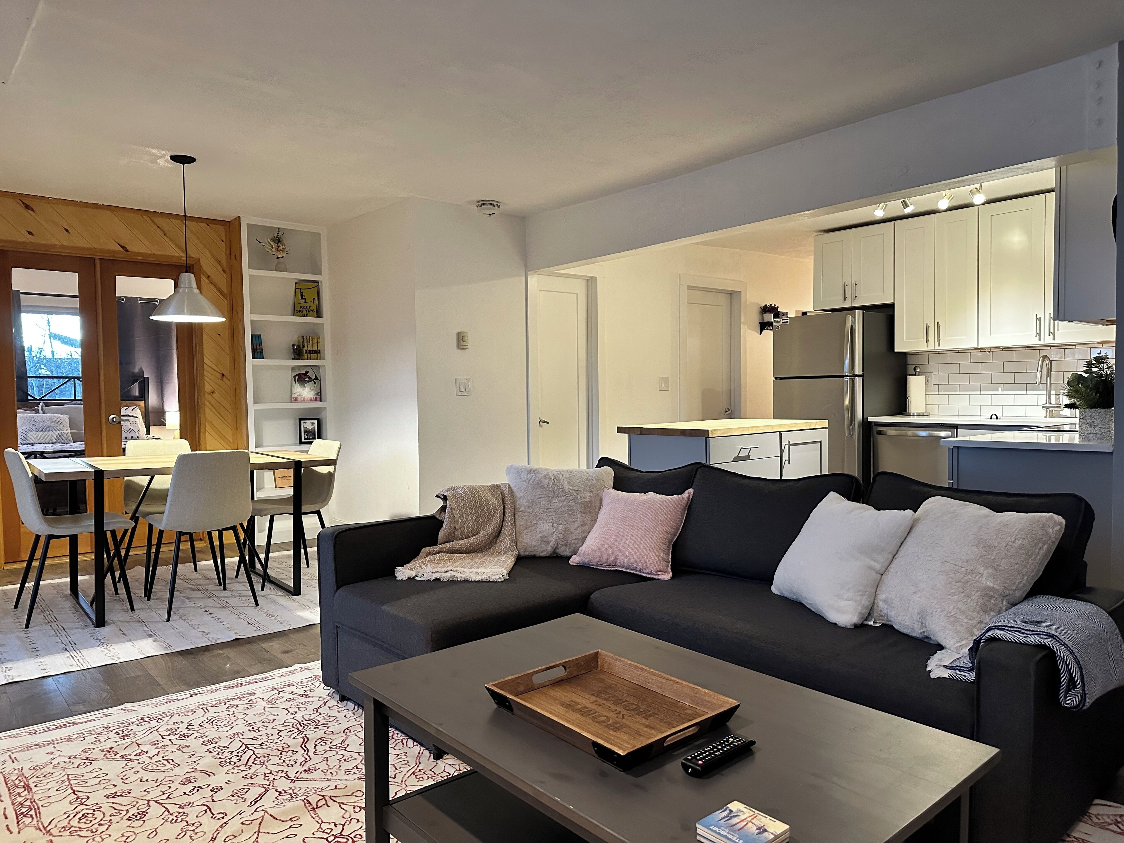 A modern living room with a sofa, coffee table, and dining area.