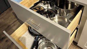 Un tiroir de cuisine contenant divers ustensiles de cuisine, notamment des casseroles, des poêles et une passoire.