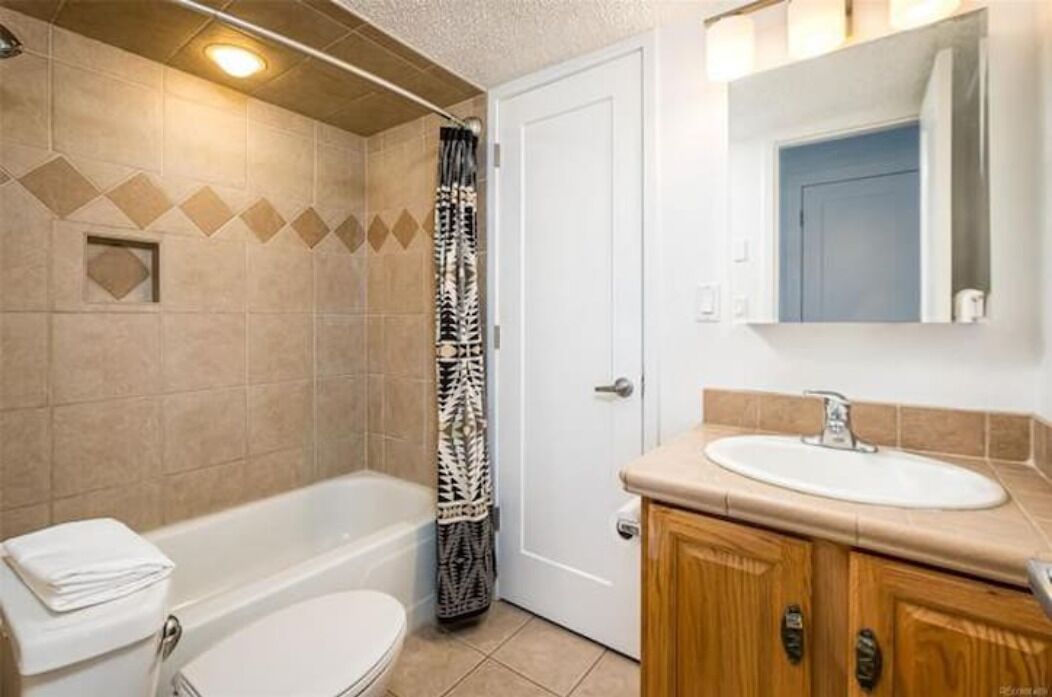 A bathroom with a bathtub, toilet, sink, and a shower curtain.