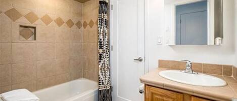 A bathroom with a bathtub, toilet, sink, and a shower curtain.
