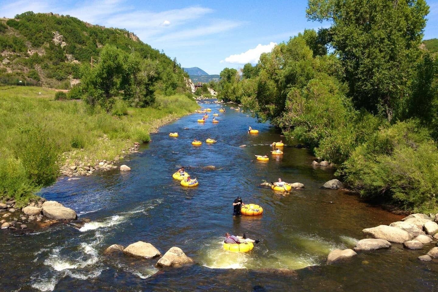 A river with multiple yellow inflatable rafts.