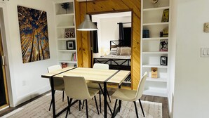 Un coin repas avec une table et des chaises en bois, un luminaire suspendu et un tapis à motifs.