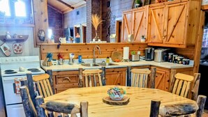 Een rustieke keuken met houten meubels, een ronde houten tafel en een witte oven.
