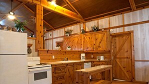 Een landelijke keuken met houten kastjes, een witte kookplaat en een houten bankje.