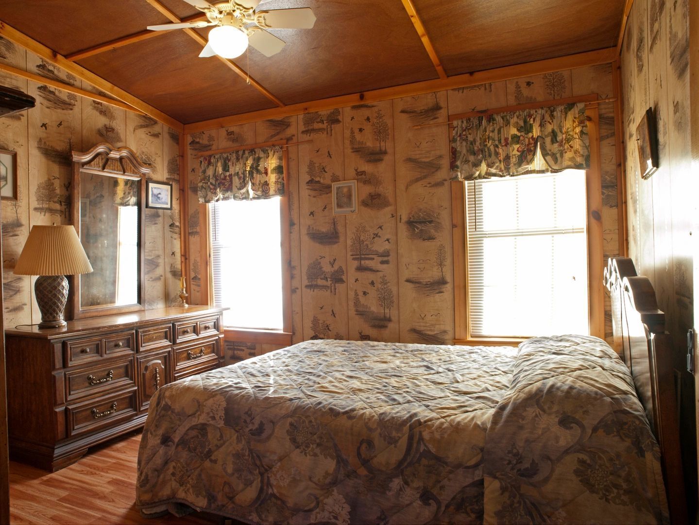 Une chambre à coucher avec un lit, une commode et un ventilateur de plafond.