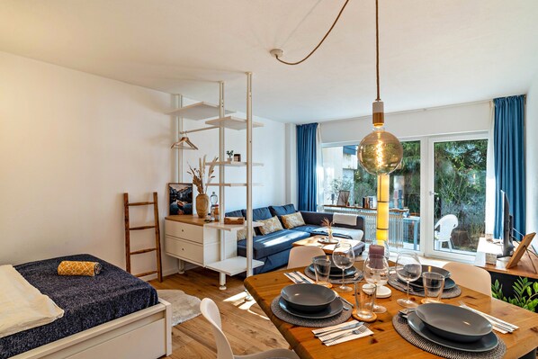 Ein modernes Wohnzimmer mit einer Couch, einem Esstisch für vier Personen und einer Treppe mit weißer Geländer.