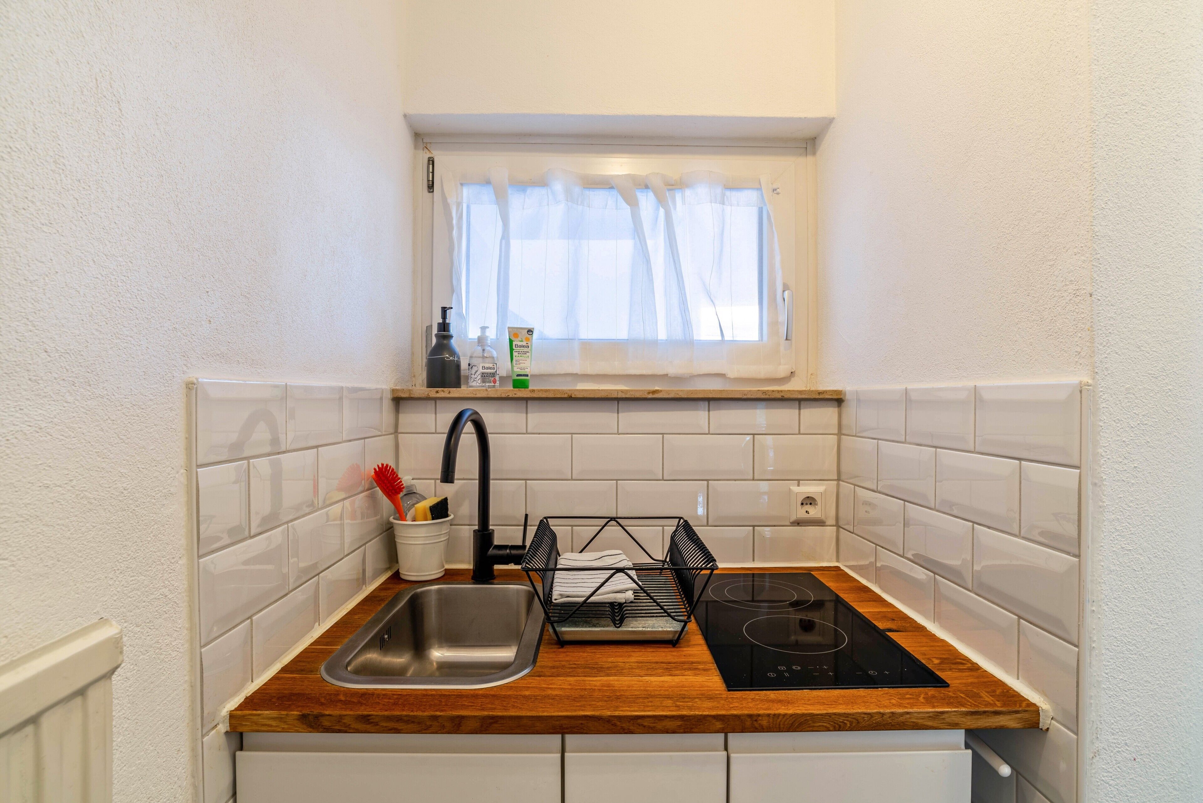 A compact kitchen with a sink, faucet, and black induction cooktop.