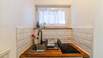 A compact kitchen with a sink, faucet, and black induction cooktop.