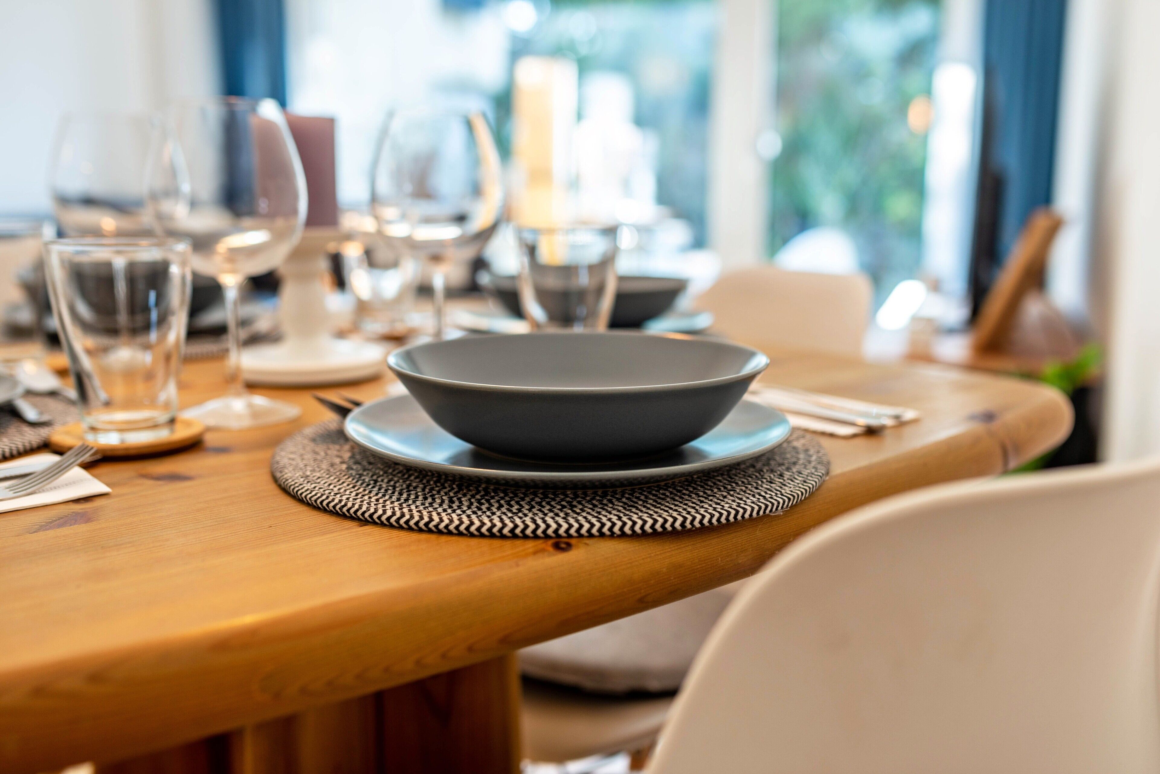 Uma mesa de jantar com um tigela, pratos e talheres.