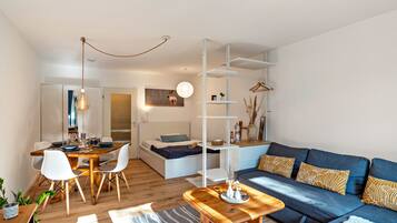 Un salon moderne avec un canapé, une table basse et un coin repas avec des chaises.