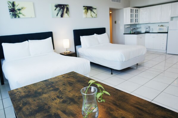 Une chambre d’hôtel avec deux lits, une table en bois et un vase avec une plante.