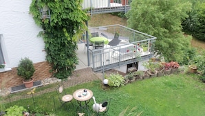 Een terras op het dak met een tafel en stoelen, omringd door potplanten en een kleine tuin.