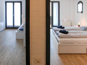 Relax in a serene space with a large bed, bedside table, and natural light pouring in through the large window.