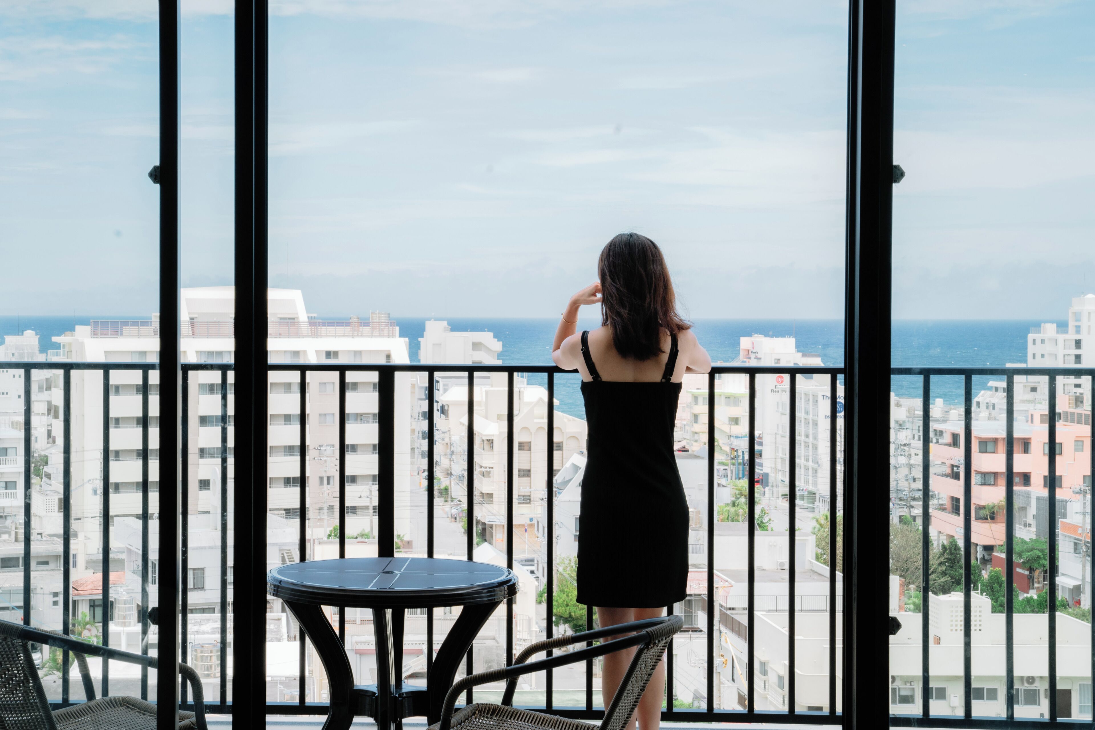 Una mujer de pie en un balcón con vistas a la ciudad y al mar.