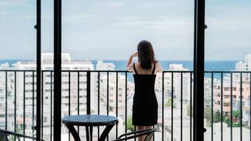 Una mujer de pie en un balcón con vistas a la ciudad y al mar.