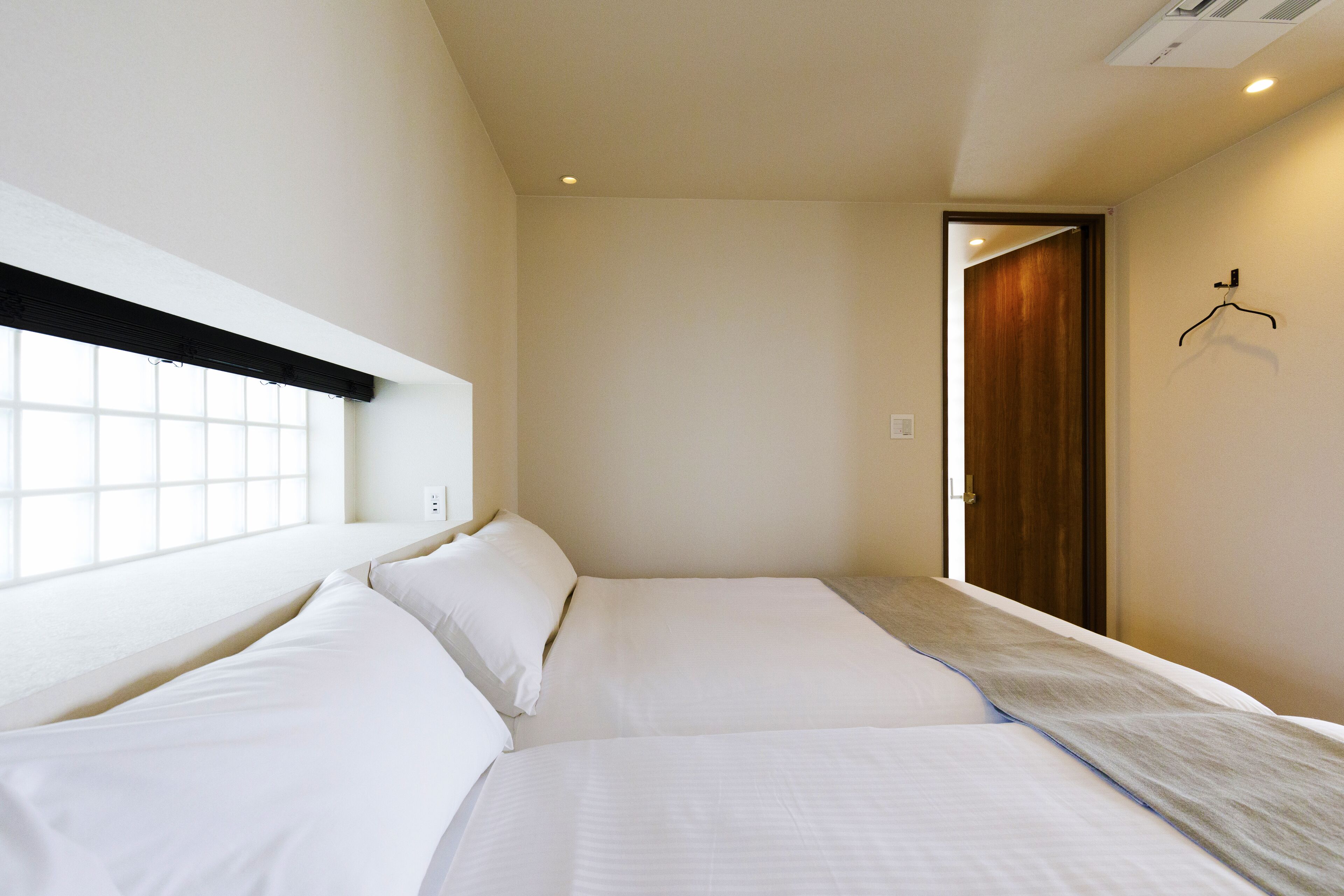Habitación de hotel con dos camas, una ventana y una puerta.