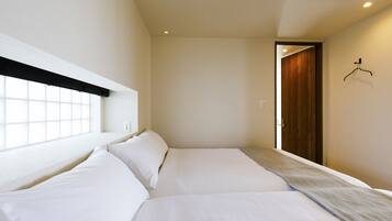Habitación de hotel con dos camas, una ventana y una puerta.