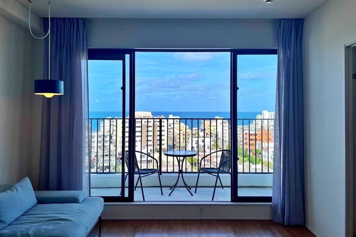 Un salon moderne doté d’un grand balcon, d’un canapé, d’une table et de deux fauteuils.