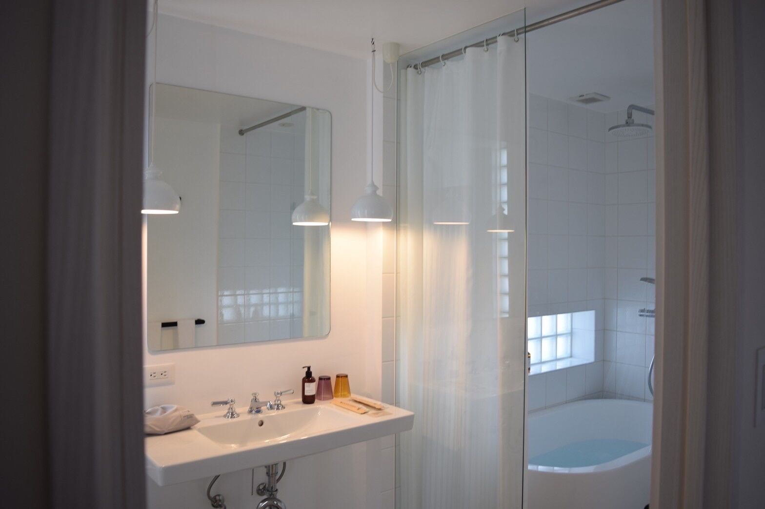 A bathroom with a white sink, mirror, and shower area.