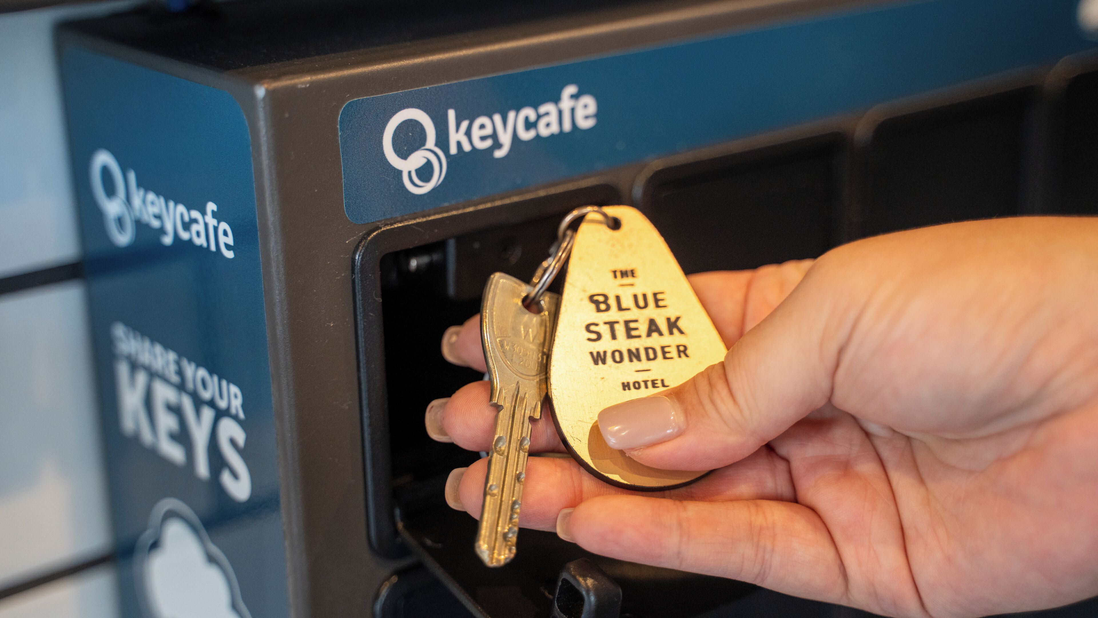 A hand inserting a key into a keycard slot labeled "The Blue Steak Wonder Hotel".