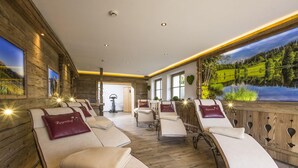 A spa room with reclining chairs, wooden walls, and a large window with a scenic view. - Chalet / Apartment Deluxe im Gartenhotel Rosenhof bei Kitzbühel (Oberndorf in Tirol)