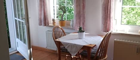 Ett mysigt rum med ett matbord, stolar, en soffa och ett fönster med gardiner.