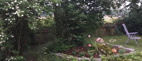 A garden with a wooden fence, a flower bed, and a folding chair.