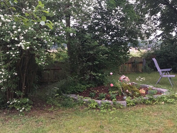 A garden with a wooden fence, a flower bed, and a folding chair.