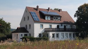 Et toetagers hus med solpaneler på taget og en balkon.