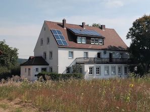 Una casa de dos pisos con paneles solares en el techo y un balcón.