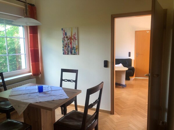 A dining area with a wooden table, chairs, and a window with curtains.