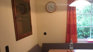 Uma área de refeições com uma mesa de madeira, um banco e um relógio na parede.