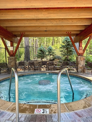 A pool with a no diving sign, a 3 1/2 ft depth marker, and a wooden deck with chairs and a stone wall.