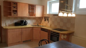 A modern kitchen with wooden cabinets, a built-in oven, and a window above the sink. - Kleine Mietidee (Markranstaedt)