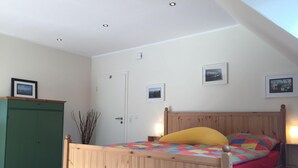 A bedroom with a wooden bed, a green wardrobe, and a skylight. - Huus Windroos Wohnung 2 (Jemgum)