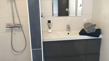 Un baño moderno con ducha, lavabo y espejo.