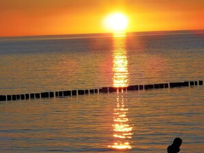 A sunset over a calm sea with a pier extending into the water. - Ferienwohnungen Seidel (Zingst)
