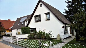 A white two-story house with a sloped roof, a small window, and a mailbox. - Ferienwohnungen Seidel (Zingst)