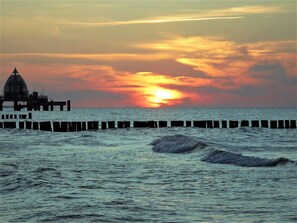 A coastal sunset with a pier and waves. - Ferienwohnungen Seidel (Zingst)