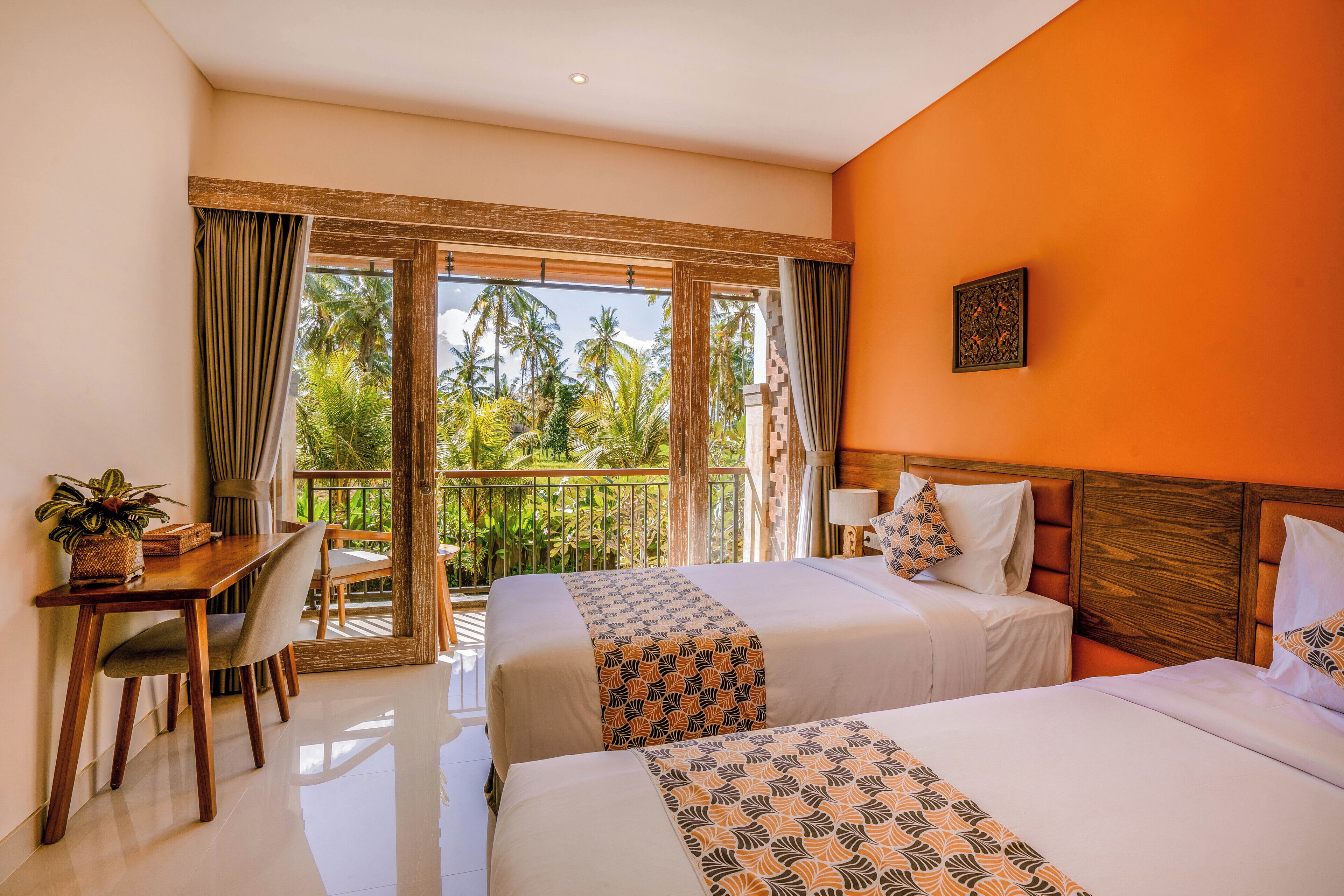 Quarto de hotel com duas camas, uma escrivaninha e varanda com vista para palmeiras.